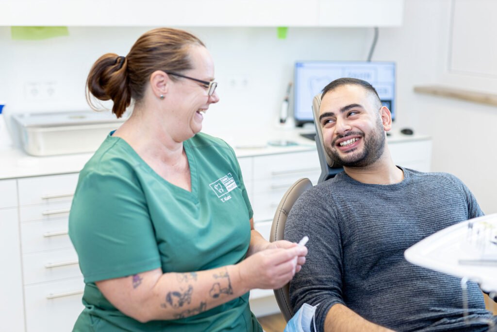 Funktionstherapie Behandlung einer Zahnarzthelferin mit einem Patienten, der auf einem Behandlungsstuhl sitzt