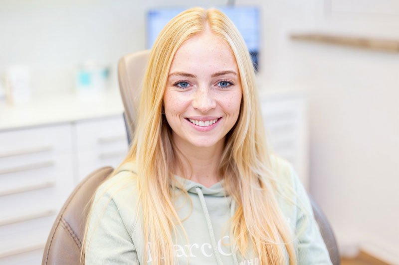 Frau lächelt strahlend nach Aligner-Therapie mit geraden Zähnen in Zahnarztpraxis